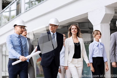 Image of business team in helmets walking along office