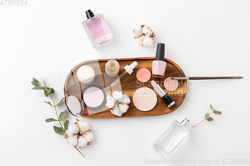 Image of makeup, perfume and cosmetics on wooden tray