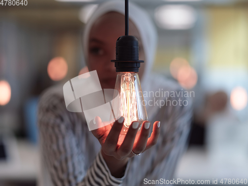 Image of african american businesswoman holding hands around light bulb