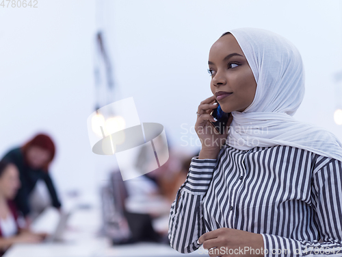 Image of African muslim businesswoman at office using smart phone