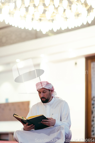 Image of muslim man praying Allah alone inside the mosque and reading islamic holly book