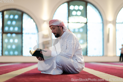 Image of muslim man praying Allah alone inside the mosque and reading islamic holly book