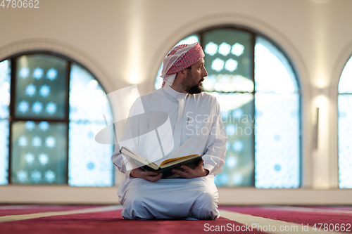 Image of muslim man praying Allah alone inside the mosque and reading islamic holly book