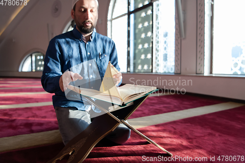 Image of muslim man praying Allah alone inside the mosque and reading islamic holly book