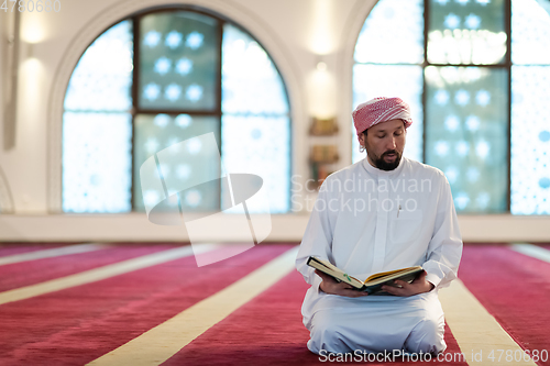 Image of muslim man praying Allah alone inside the mosque and reading islamic holly book