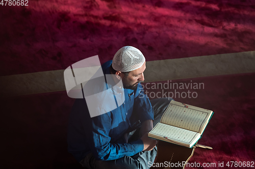 Image of muslim man praying Allah alone inside the mosque and reading islamic holly book