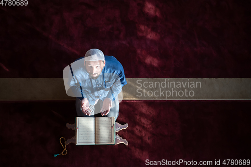 Image of muslim man praying Allah alone inside the mosque and reading islamic holly book