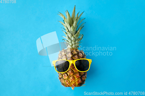 Image of pineapple in yellow sunglasses on blue background