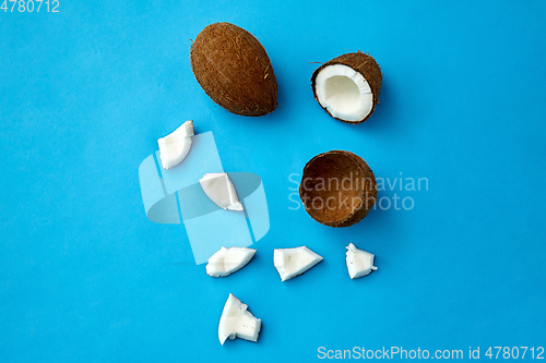 Image of whole and cracked coconut on blue background