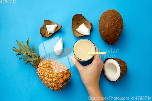 Image of hand with pineapple coconut drink with paper straw