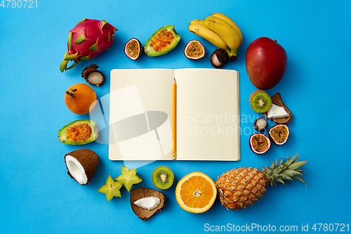 Image of exotic fruits around notebook with empty pages