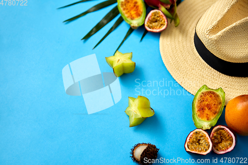 Image of straw hat and exotic fruits on blue background