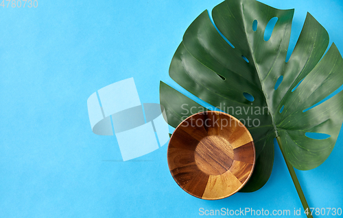 Image of wooden plate and monstera deliciosa leaf