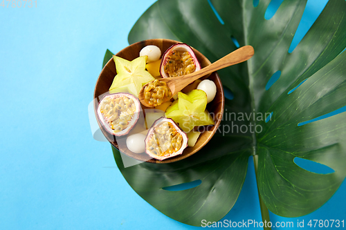 Image of mix of exotic fruits in wooden plate with spoon