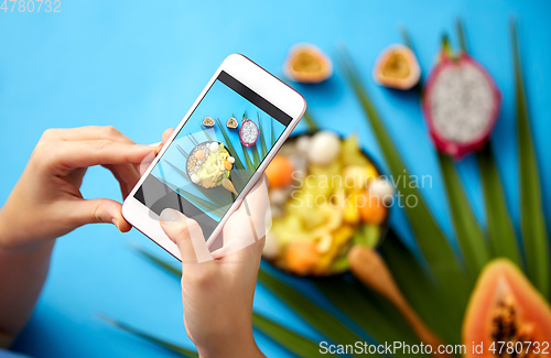 Image of hands taking photo of exotic fruits on smartphone