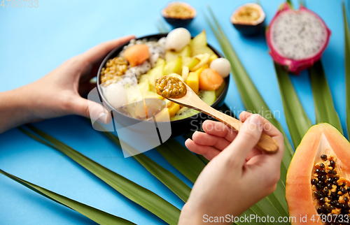 Image of hands with mix of exotic fruits and wooden spoon