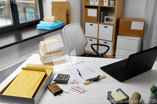 Image of laptop and parcels on table at post office