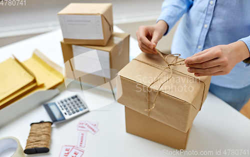 Image of woman packing parcel and tying rope at post office