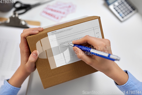 Image of close up of hands filling form on parcel at office