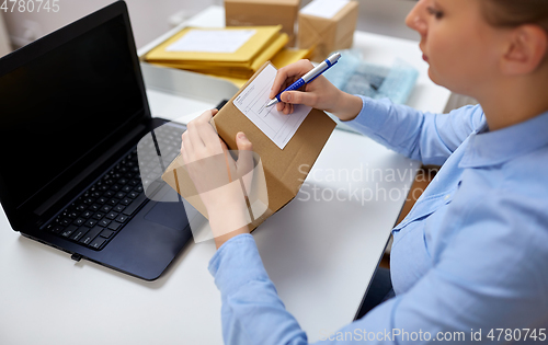 Image of close up of woman filling postal form at office