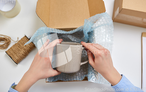 Image of hands packing mug to parcel box at post office