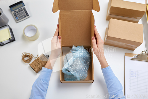 Image of hands packing mug to parcel box at post office