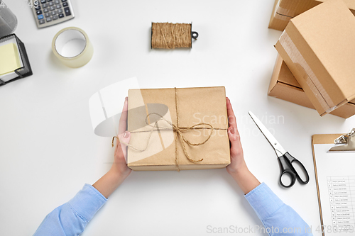 Image of hands with parcel box tied by rope at post office