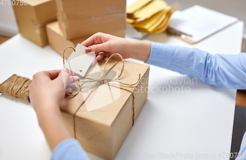 Image of hands tying name tag to parcel box at post office