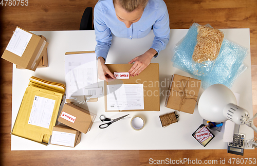 Image of woman sticking fragile mark to parcel box