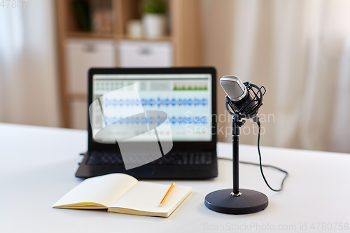 Image of microphone, laptop and notebook on table