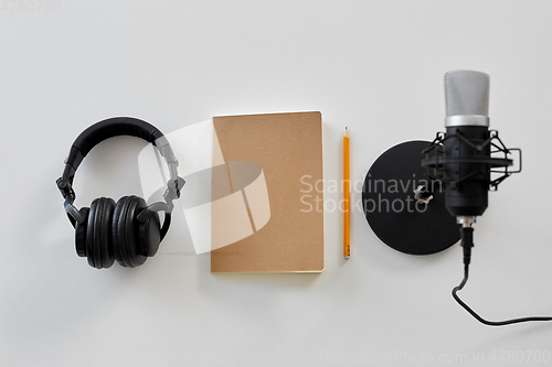 Image of headphones, microphone and notebook with pencil