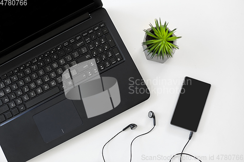 Image of close up of laptop, smartphone and earphones