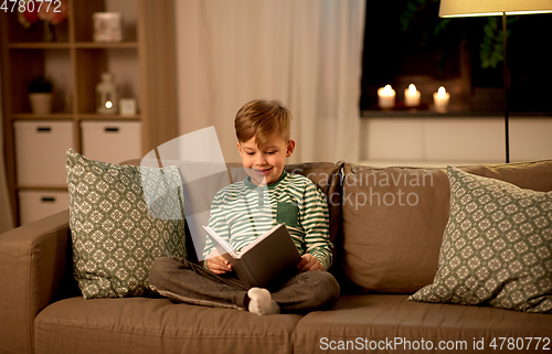 Image of happy little boy reading book at home