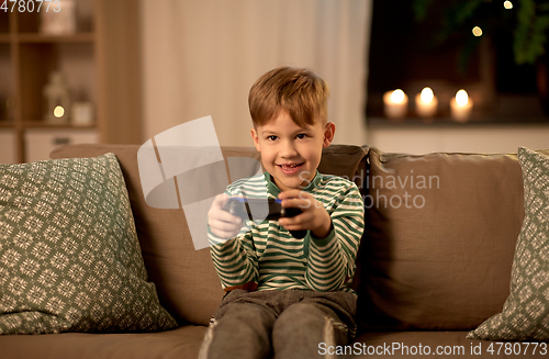 Image of little boy with gamepad playing video game at home