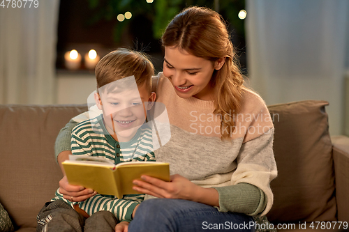 Image of happy mother and son reading book sofa at home