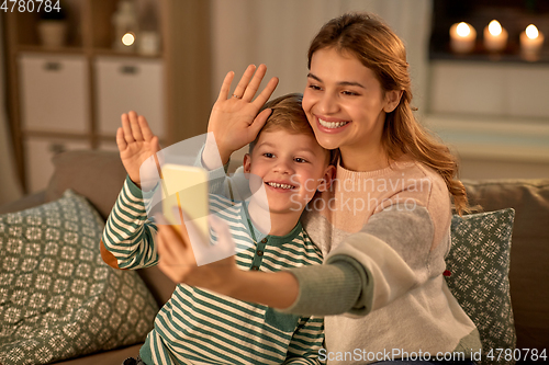 Image of mother and son taking selfie by smartphone at home