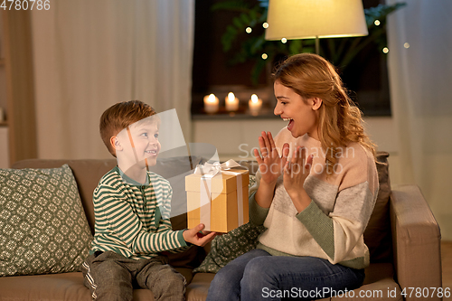 Image of little son giving present to mother at home