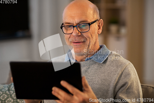 Image of happy senior man with tablet computer at home