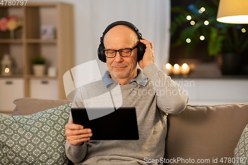 Image of senior man with tablet pc and headphones at home