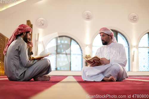 Image of two muslim people in mosque reading quran together concept of islamic education