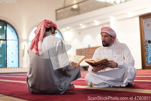 Image of two muslim people in mosque reading quran together concept of islamic education