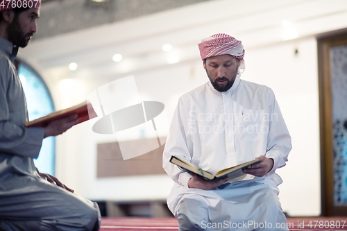 Image of two muslim people in mosque reading quran together concept of islamic education