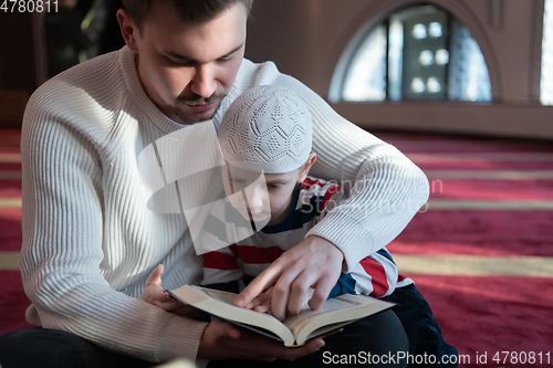 Image of  father and son in mosque praying and reading holly book quran together islamic education concept