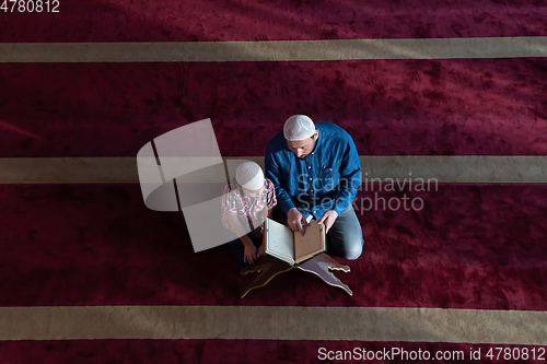 Image of father and son reading holly book quran together islamic education concept