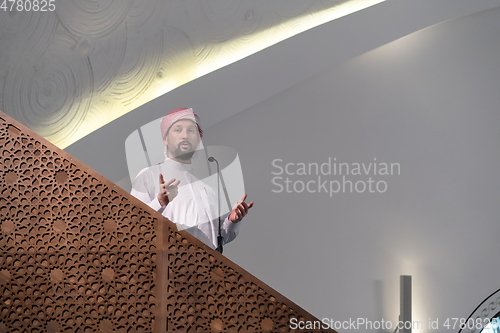 Image of Muslims young arabic Imam has a speech on friday afternoon prayer in mosque.