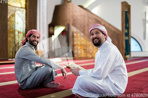 Image of two muslim people in mosque reading quran together concept of islamic education