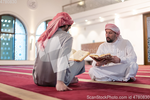 Image of two muslim people in mosque reading quran together concept of islamic education