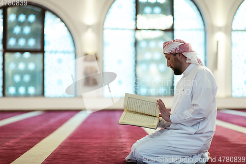 Image of muslim man praying Allah alone inside the mosque and reading islamic holly book