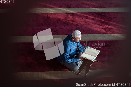 Image of muslim man praying Allah alone inside the mosque and reading islamic holly book