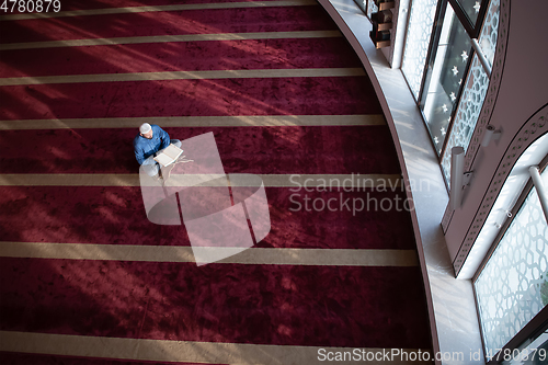 Image of muslim man praying Allah alone inside the mosque and reading islamic holly book